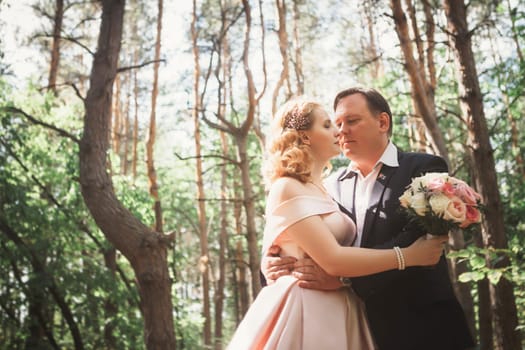 bride and groom kiss on the background of trees and forest.