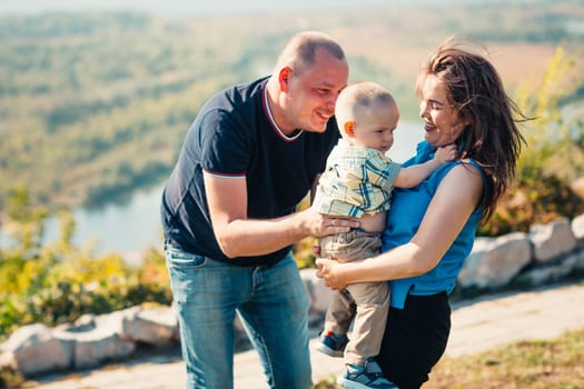 Happy family with baby son on nature background.