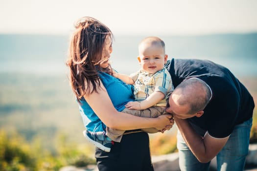 Happy family with baby son on nature background.