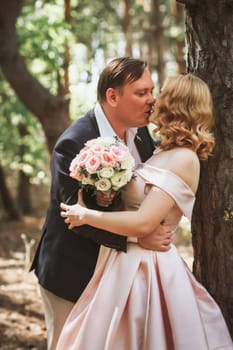 bride and groom kiss on the background of trees and forest.