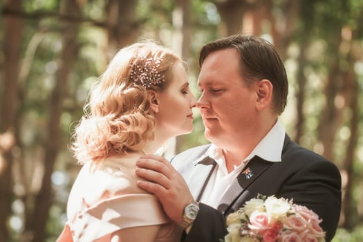bride and groom kiss on the background of trees and forest.