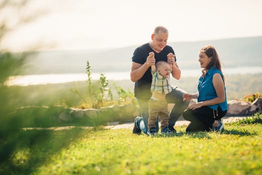 Happy family with baby on green grass.