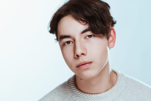 Studio portrait young man in grey sweater on white background.