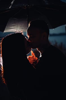 young man and woman under an umbrella and rain.