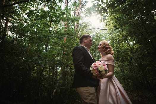 bride and groom dancing in the forest background and sunlight.
