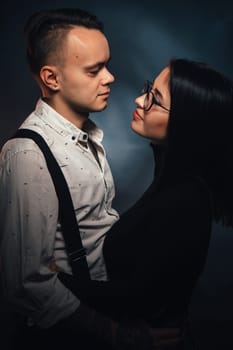 Couple in fashionable clothes on a dark background with smoke.