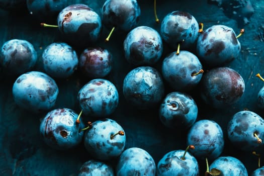 many fresh plums on blue background close up