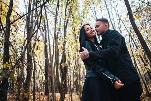 The girl and the guy are walking in the autumn forest.