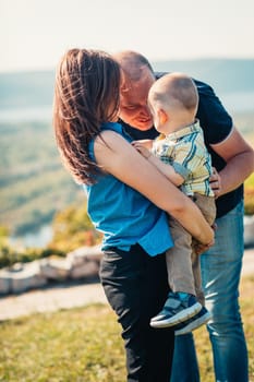 Happy family with baby son on nature background.
