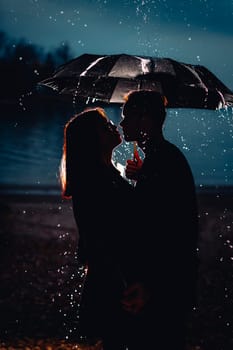 young man and woman under an umbrella and rain.
