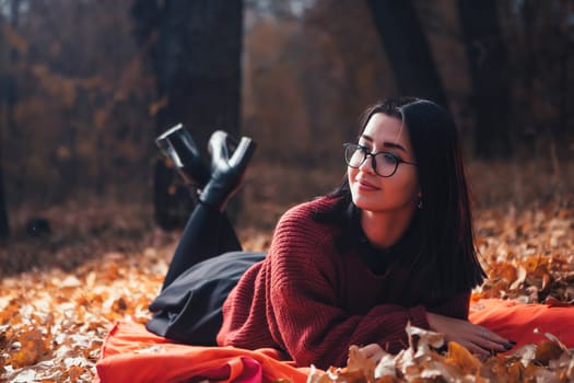 Girl lying on the plaid in autumn forest, nature background.