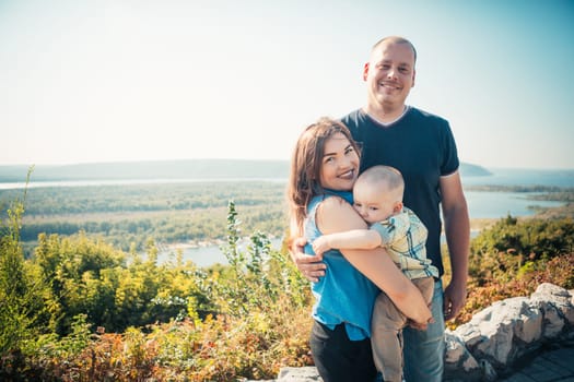 Happy family with baby son on nature background.