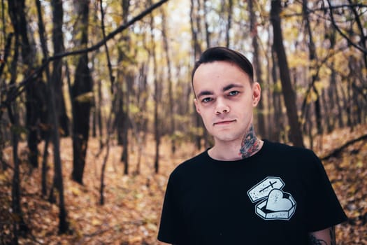portrait of a man with tattoo in the autumn forest.