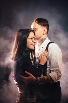 Couple in fashionable clothes on a dark smoky background.