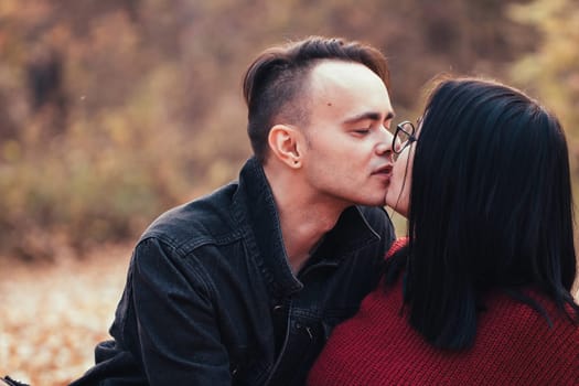 young man and young woman are sitting on a plaid in an autumn forest.