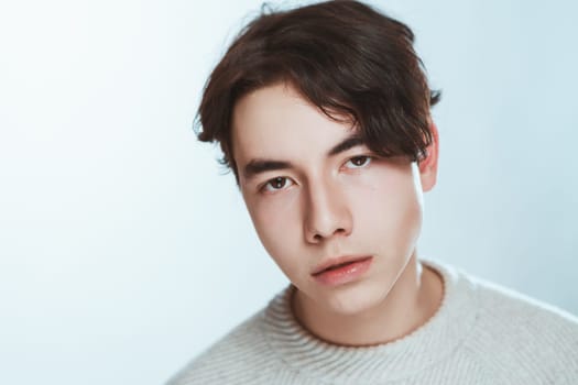 Studio portrait young man in grey sweater on white background.