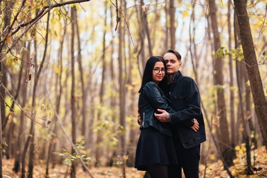 The girl and the guy are walking in the autumn forest.