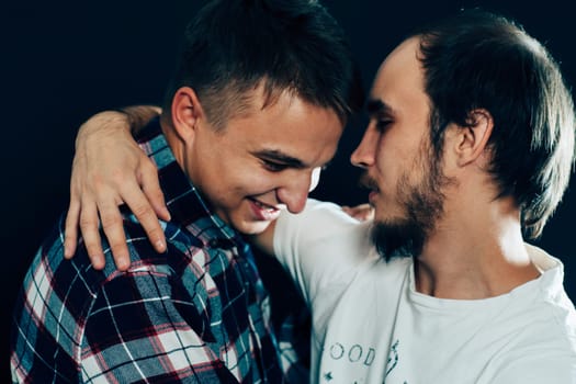 two guys hugging on a dark background.