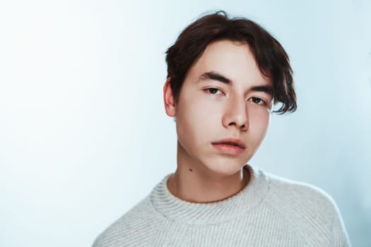 Studio portrait young man in grey sweater on white background.