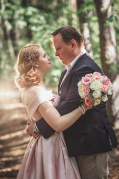 bride and groom on the background of trees and forest sun.