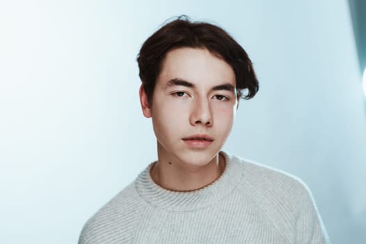 Studio portrait young man in grey sweater on white background.