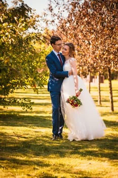 Beautiful stylish bride and groom on garden background.