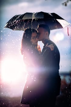 young man and woman under an umbrella and rain.