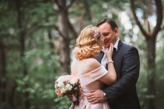 bride and groom kissing in the summer forest.