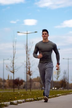 The handsome young sporty man is jogging at the street outdoors.