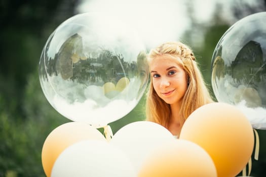 portrait of young girl with balloons on nature background.