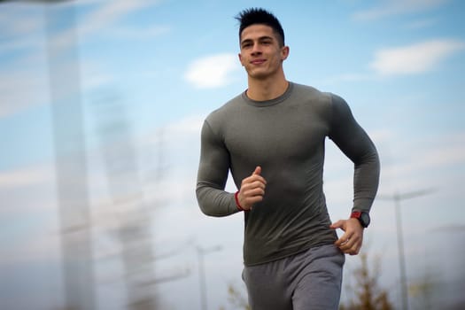 The young handsome sporty man is jogging or running outdoors.