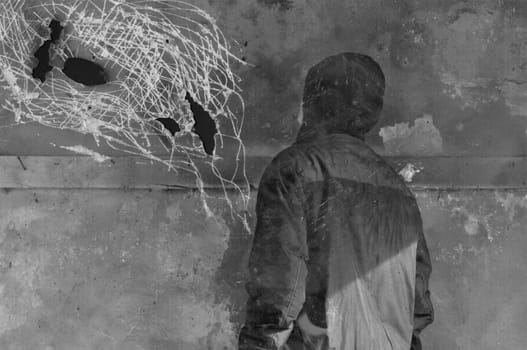 Man looking at strange shapes on textured wall surface. Black and white on scratched paper.