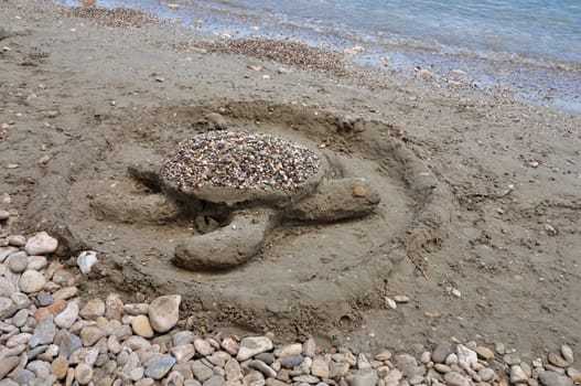 Sea turtle sand sculpture on sandy beach. Summer holidays.