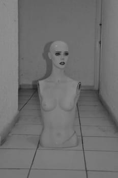 Spooky broken mannequin dummy doll in dark basement. Black and white.