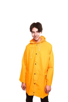 portrait of a teen guy in a yellow raincoat brunette in the studio.