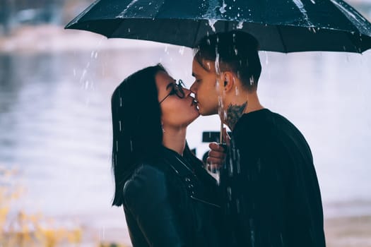 young man and woman under an umbrella and rain.