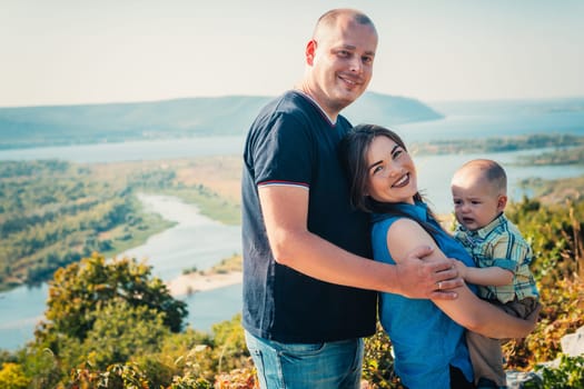 Happy family with baby son on nature background.