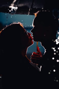 young man and woman under an umbrella and rain.