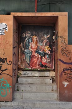 ATHENS, GREECE - APRIL 15, 2014: Urban street art abstract graffiti painting of woman with cupid angels and pigeons on rusty gate of under construction building.