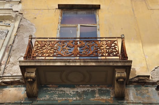 Winged female figure rusty floral pattern and swans on balcony balustrade of abandoned neoclassical house. Athens Greece.