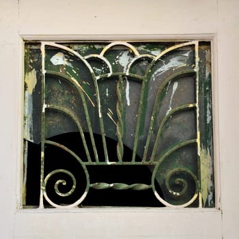 Abstract cosmic tree of life with spiral roots and seven branches extending up towards the heavens. Vintage iron motif on old window.