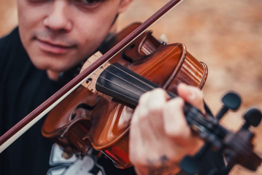 young man playing violin in the autumn forest.