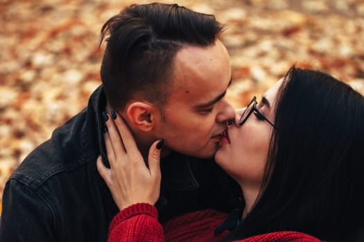 young man and young woman are sitting on a plaid in an autumn forest.
