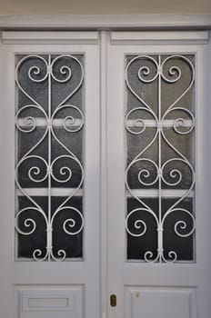 White wooden door frame with glass lite and vintage metal pattern.