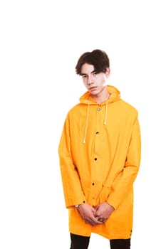 portrait of a teen guy in a yellow raincoat brunette in the studio.