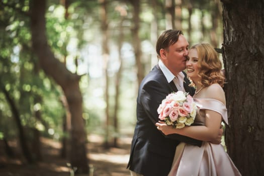 bride and groom kiss on the background of trees and forest.