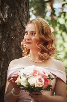 portrait of a beautiful bride standing near a tree.