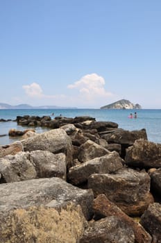 ZAKYNTHOS, GREECE - JULY 17, 2014: People swimming at the beach in Keri. Rock pier blue sea and sky horizon.