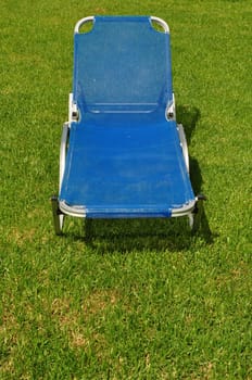 Reclining lawn chair on green grass background. Garden furniture.
