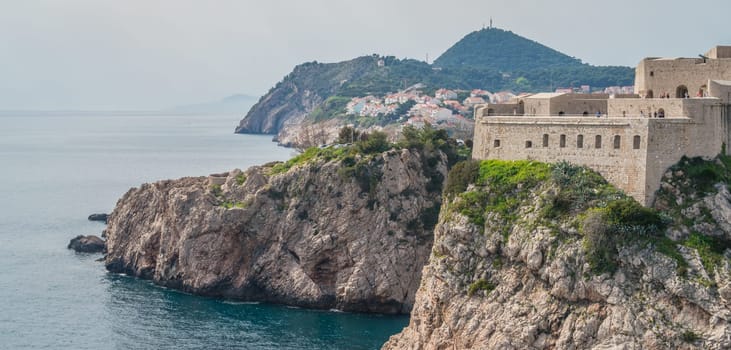 Dubrovnik, Croatia - April 2018 : Rocky coast alongside Dubrovnik Old Town massive defence walls of fortress Bokar